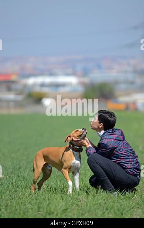 Giovani dai capelli corti donna abbracci e dà affetto per il suo cane Foto Stock