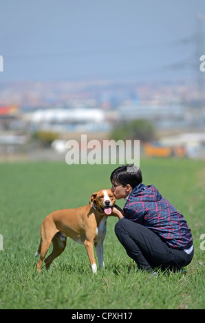 Giovani dai capelli corti donna abbracci e dà affetto per il suo cane Foto Stock