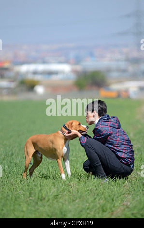 Giovani dai capelli corti donna abbracci e dà affetto per il suo cane Foto Stock