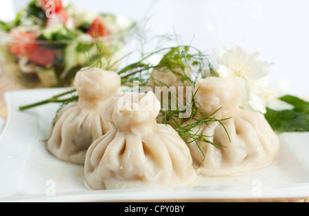 Georgian khinkali con insalata su un piatto bianco Foto Stock