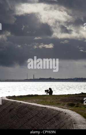 Bird watcher a Farlington paludi umide dal mare sulla parete tempestoso giorno Foto Stock