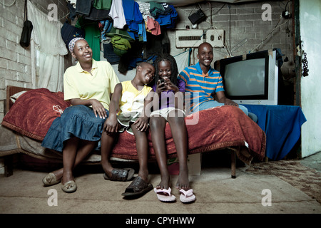 Famiglia africana si siede insieme su un letto in ambienti interni Foto Stock