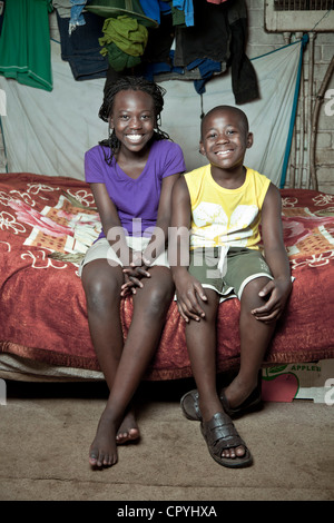 Due giovani fratelli africani si siedono su un letto in ambienti interni Foto Stock