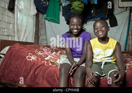 Due giovani fratelli africani si siedono su un letto in ambienti interni Foto Stock