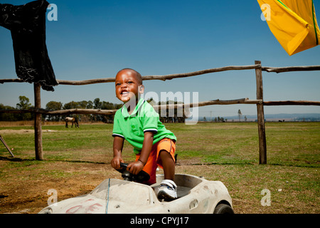 Giovane bambino africano giocando al di fuori della sua casa rurale Foto Stock