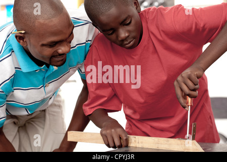 African padre e figlio avvitando una vite in un pezzo di legno Foto Stock