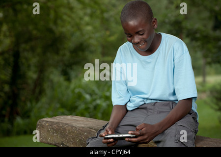 Bambino africano giocando con una console di gioco al di fuori Foto Stock