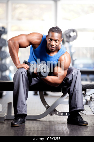 Muscolare giovane uomo nero sollevamento pesi nella palestra Foto Stock