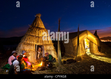 Il Perù, Provincia di Puno, il lago Titicaca, isole galleggianti di Uros, serata famiglia pasto a casa riscaldata con secchi reed Foto Stock