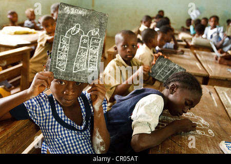 Una ragazza mantiene la sua ardesia per mostrare la soluzione ha scoperto un problema di matematica durante la classe al Groupe Scolaire Bondoukou Est Foto Stock