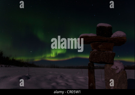 Silhouette di Inuit uomo di pietra, inukshuk, inuksuk, pietra landmark o cairn Northern Lights, polari o aurora Aurora Boreale Foto Stock