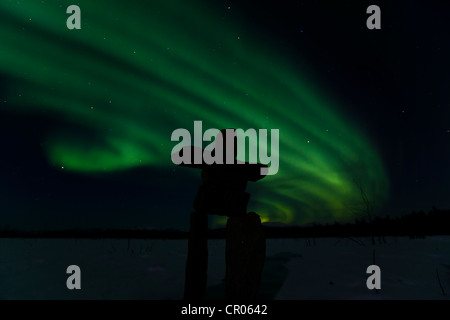 Silhouette di Inuit uomo di pietra, inukshuk oder inuksuk, pietra landmark o cairn, polare settentrionale luci, Aurora boreale, verde Foto Stock