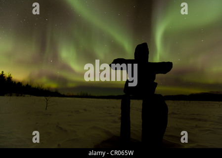 Silhouette di Inuit uomo di pietra, inukshuk oder inuksuk, pietra landmark o cairn, polare settentrionale luci, Aurora boreale, verde Foto Stock