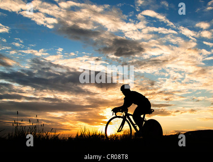 Silhouette di un ciclista in tramonto Foto Stock