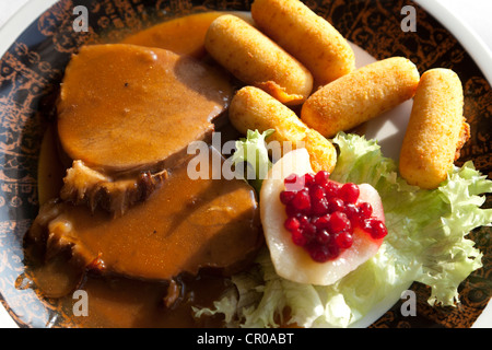 Arrosto di maiale con salsa, crocchette di patate e pera con mirtilli rossi Foto Stock