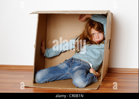 Ragazza che gioca in un vuoto di scatola di cartone Foto Stock