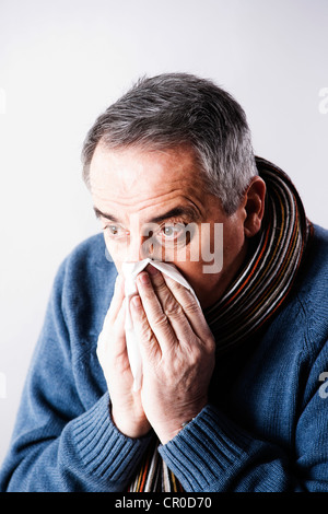 Uomo anziano soffia il naso Foto Stock