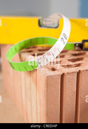 Bolla di livello e un nastro di misurazione su un mattone Foto Stock