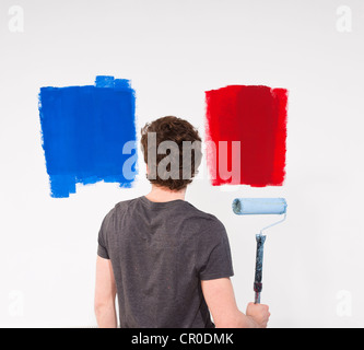 Giovane pittura un muro con campioni di vernice Foto Stock