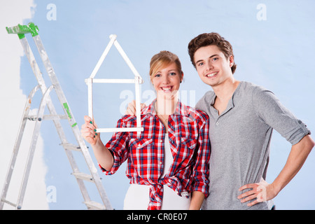 Coppia giovane tenendo un ripiegamento del falegname righello nella forma di una casa Foto Stock