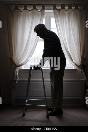 Il vecchio uomo titolare di pensione o di rendita con ZIMMER TELAIO A PIEDI IN CASA DI RE - Pensionati PENSIONE DI VECCHIAIA pensionati solo solitario fragile CAREHOME CAREGIVERS REGNO UNITO Foto Stock