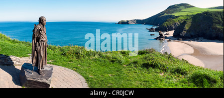 Statua di San Carannog si affaccia su un panorama della spiaggia idilliaca a Llangrannog West Wales Foto Stock