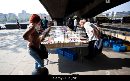 I clienti che navigano in libri di seconda mano si trova sotto Waterloo Bridge, Southbank, Londra, Inghilterra, Regno Unito. Foto Stock