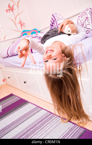 Ragazza, 9, giacente con un peluche sul suo letto Foto Stock