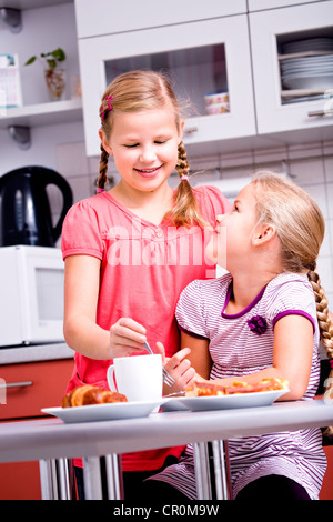 Due ragazze, sorelle avente la colazione in cucina Foto Stock