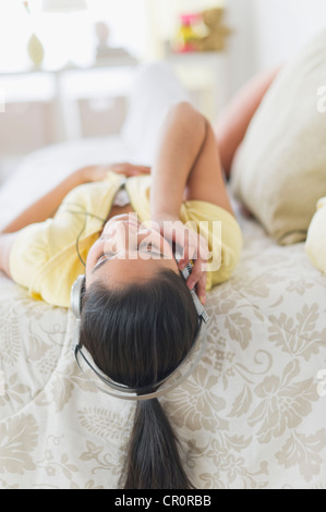 Stati Uniti d'America, New Jersey, Jersey City, ragazza (12-13) giacente sul letto con le cuffie Foto Stock