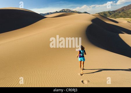 Donna ispanica in esecuzione sulla duna di sabbia Foto Stock