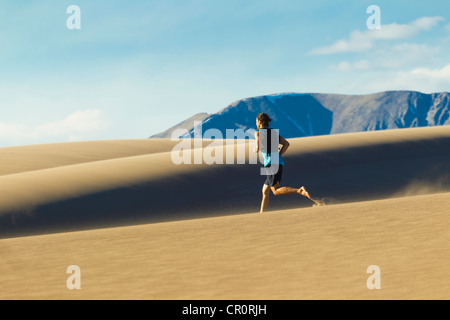 Uomo ispanico in esecuzione sulla duna di sabbia Foto Stock