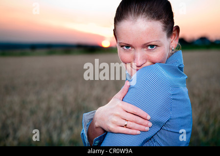 Giovane donna guardando sopra la sua spalla, ritratto, all'aperto Foto Stock