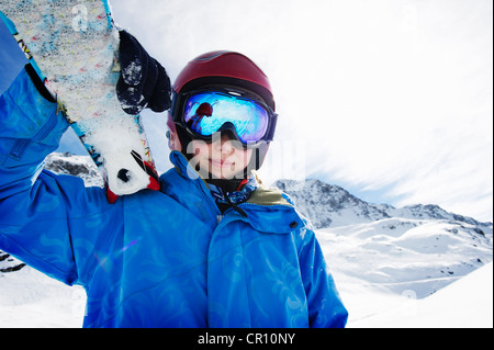 Ragazzo tenendo gli sci sulla montagna innevata Foto Stock