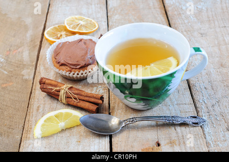 Tè, tortina, bastoncini di cannella e la fetta di limone su sfondo di legno Foto Stock