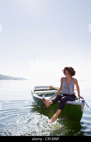 Donna piedi penzolanti da barca nel lago Foto Stock