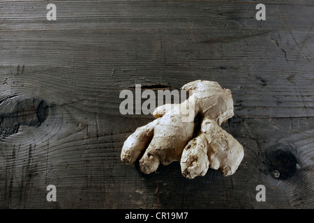 Lo zenzero (Zingiber officinale) Rizoma su un rustico di una superficie di legno Foto Stock