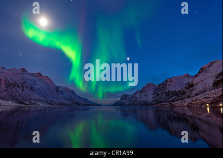 Northern Lights casting la loro riflessione in una baia circondata da montagne Foto Stock