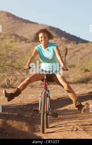 Donna in bicicletta nel paesaggio del deserto Foto Stock