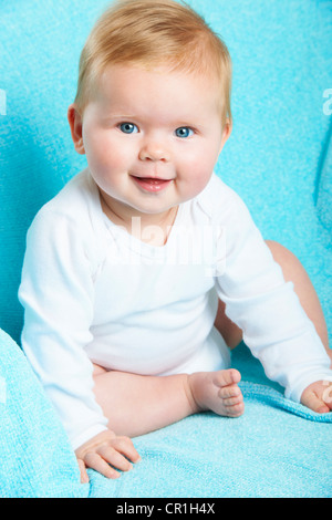 Sorridente infante seduto sulla coperta di blu Foto Stock