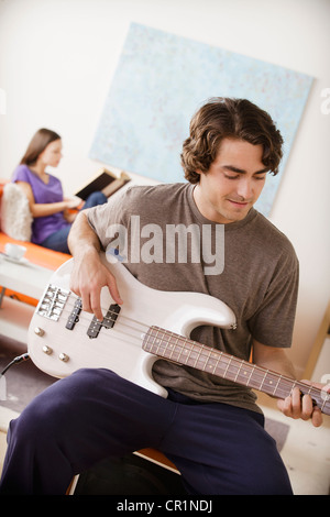 Stati Uniti, California, Los Angeles, giovane di suonare una chitarra elettrica, una giovane donna in background Foto Stock