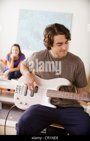 Stati Uniti, California, Los Angeles, giovane di suonare una chitarra elettrica, una giovane donna in background Foto Stock