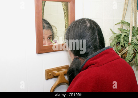 Donna anziana mettendo sul eyeliner e trucco. Foto Stock