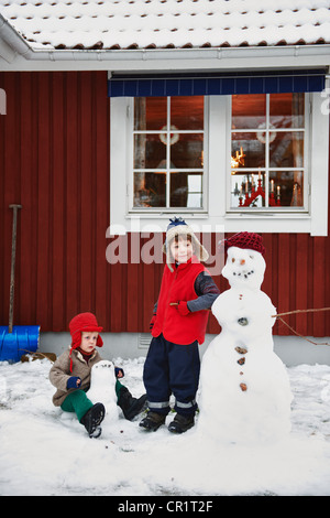 Ragazzi facendo pupazzi di neve insieme Foto Stock