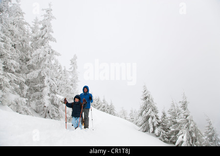 Padre e figlio con le racchette da neve su pendio Foto Stock