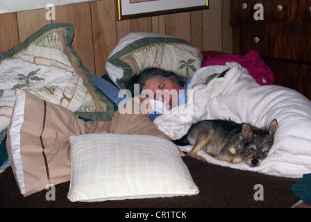 Signora anziana che dorme sul letto con il suo cane. Foto Stock