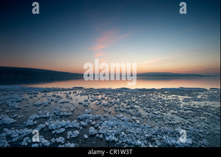 Pezzi di ghiaccio che giace sulla superficie ghiacciata sulla riva di Reichenau Isola dopo il tramonto, Baden-Wuerttemberg, Germania, Europa Foto Stock