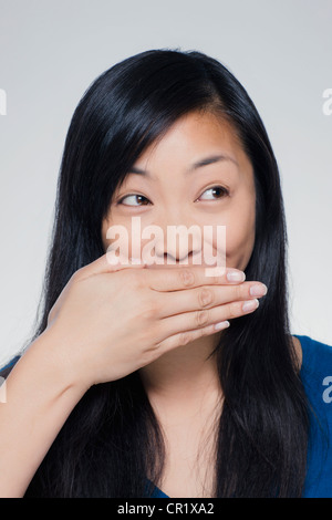 Studio Ritratto di giovane donna che copre la bocca Foto Stock