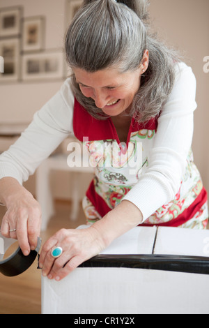 Donna anziana incarto di scatola di cartone Foto Stock