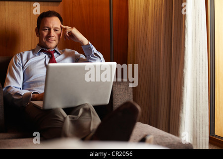 Uomo d affari con computer portatile in camera di albergo Foto Stock